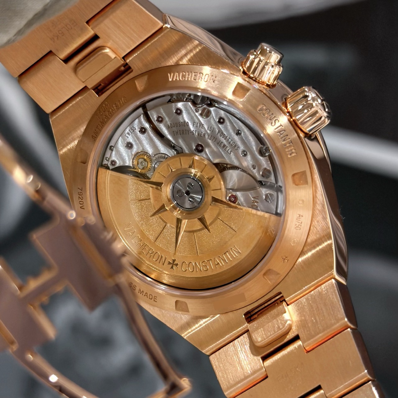 Механизм Vacheron Constantin Caliber 5110 DT через прозрачную заднюю крышку Мануфактурный механизм Vacheron Constantin Caliber 5110 DT с автоматическим подзаводом и золотым ротором в форме розы ветров, видимый через прозрачную заднюю крышку Overseas Dual Time
