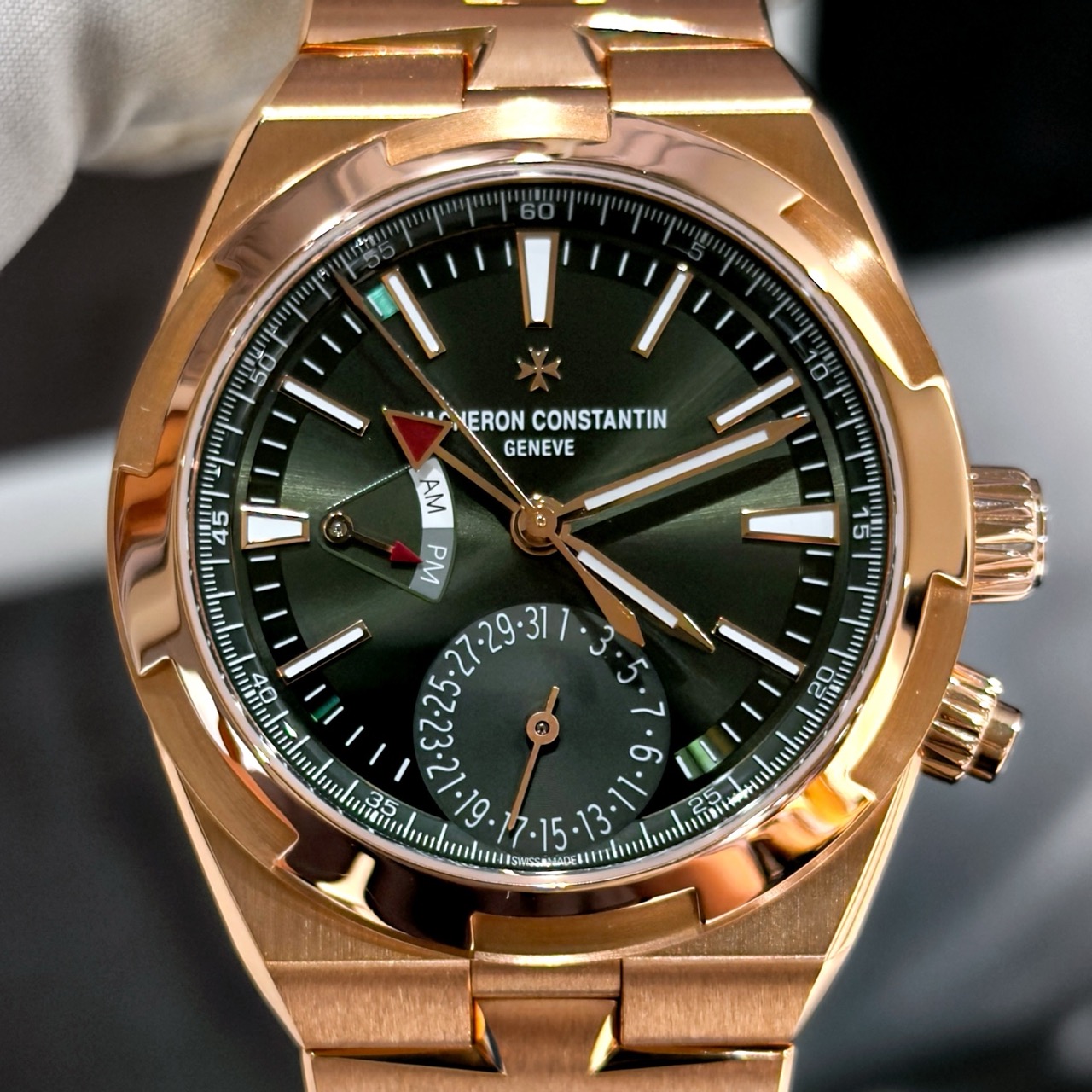 Зелёный циферблат Vacheron Constantin Overseas Dual Time Sunburst Green крупным планом Зелёный лакированный циферблат Vacheron Constantin Overseas Dual Time ref. 7920V/210R-B965 с эффектом sunburst, красными акцентами на стрелке второго часового пояса, указателем даты на 6 часах и индикатором день/ночь